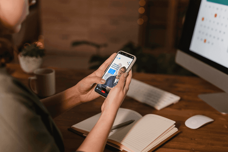 Personne assise à son bureau de travail et qui regarde sur son téléphone la vidéo de WeSoft sur l'émission des factures dans le cadre de la RFE